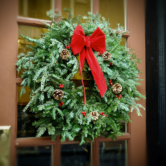 christmas wreath hanging in window of brick apartment building with flower box below, antiqued colors