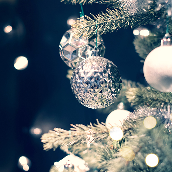 Closeup of silver bauble hanging from a decorated Christmas tree