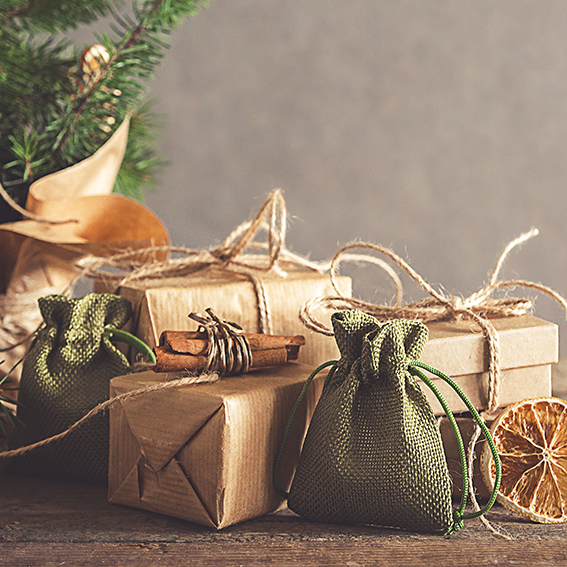 Christmas and zero waste, eco friendly packaging. Woman is wrapping gifts in craft paper on a wooden table, ecological Christmas holiday concept, eco decor