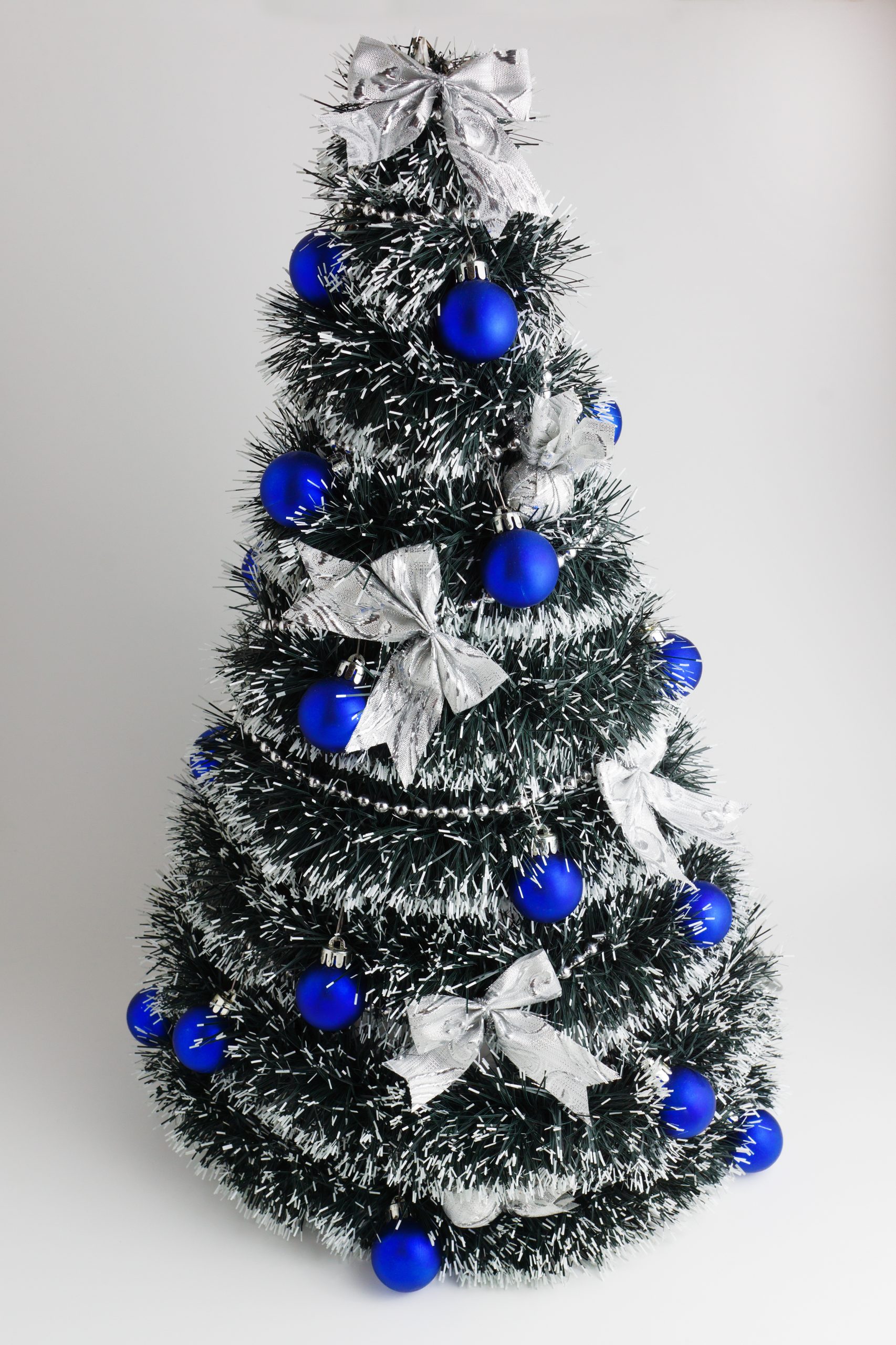 artificial pine decorated with blue spheres and a silver tape with bows