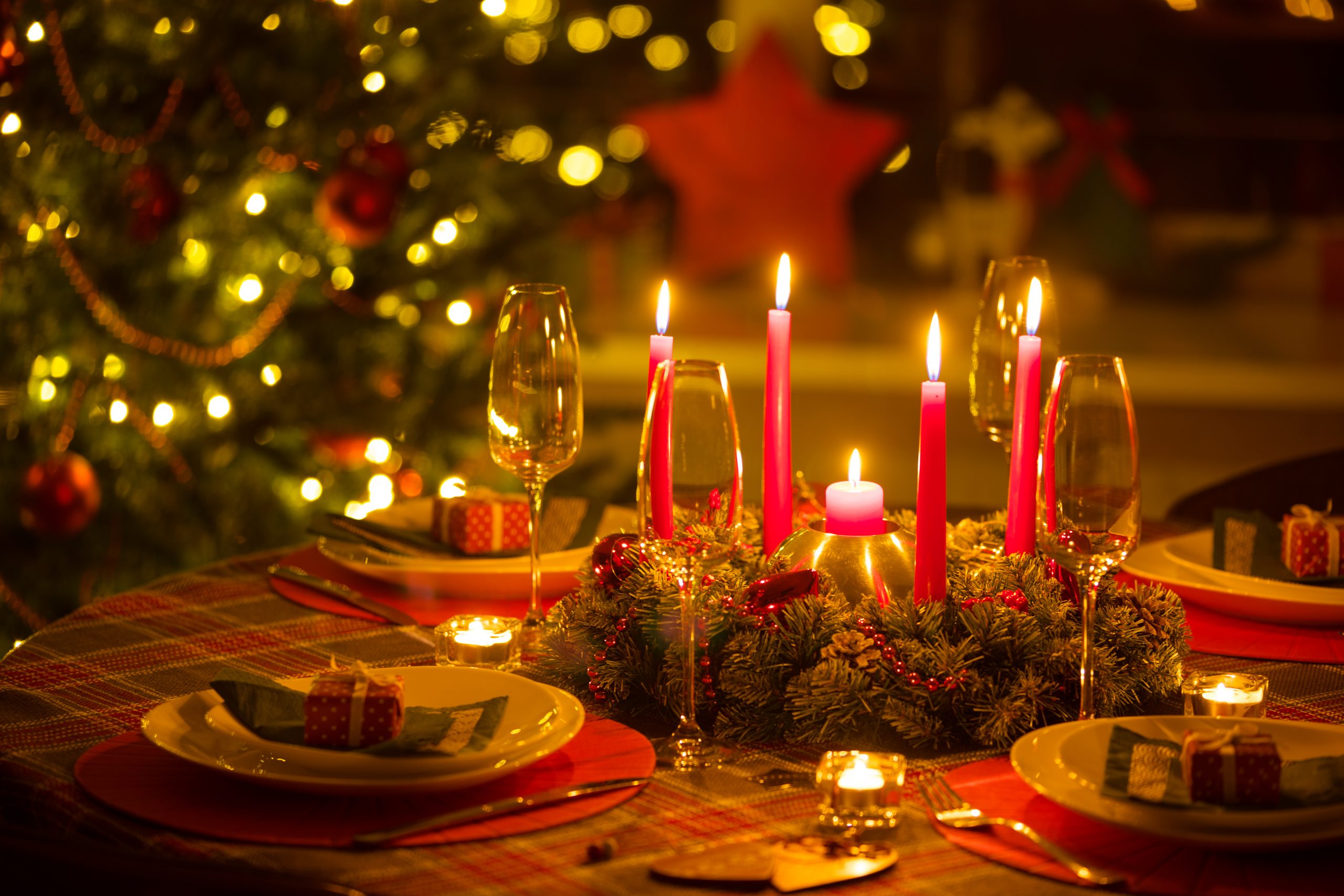 beautifully decorated Christmas table with candles and glasses near the Christmas tree