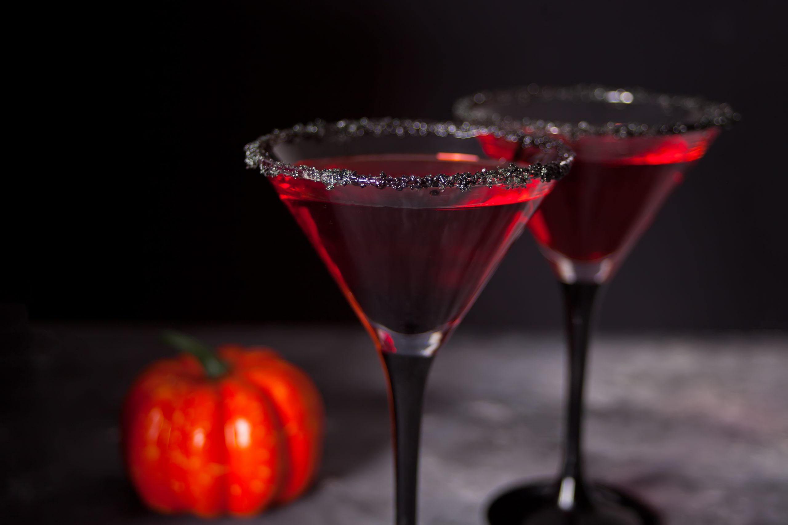 Two glasses with red cocktail, dried roses for Halloween party on the dark background.
