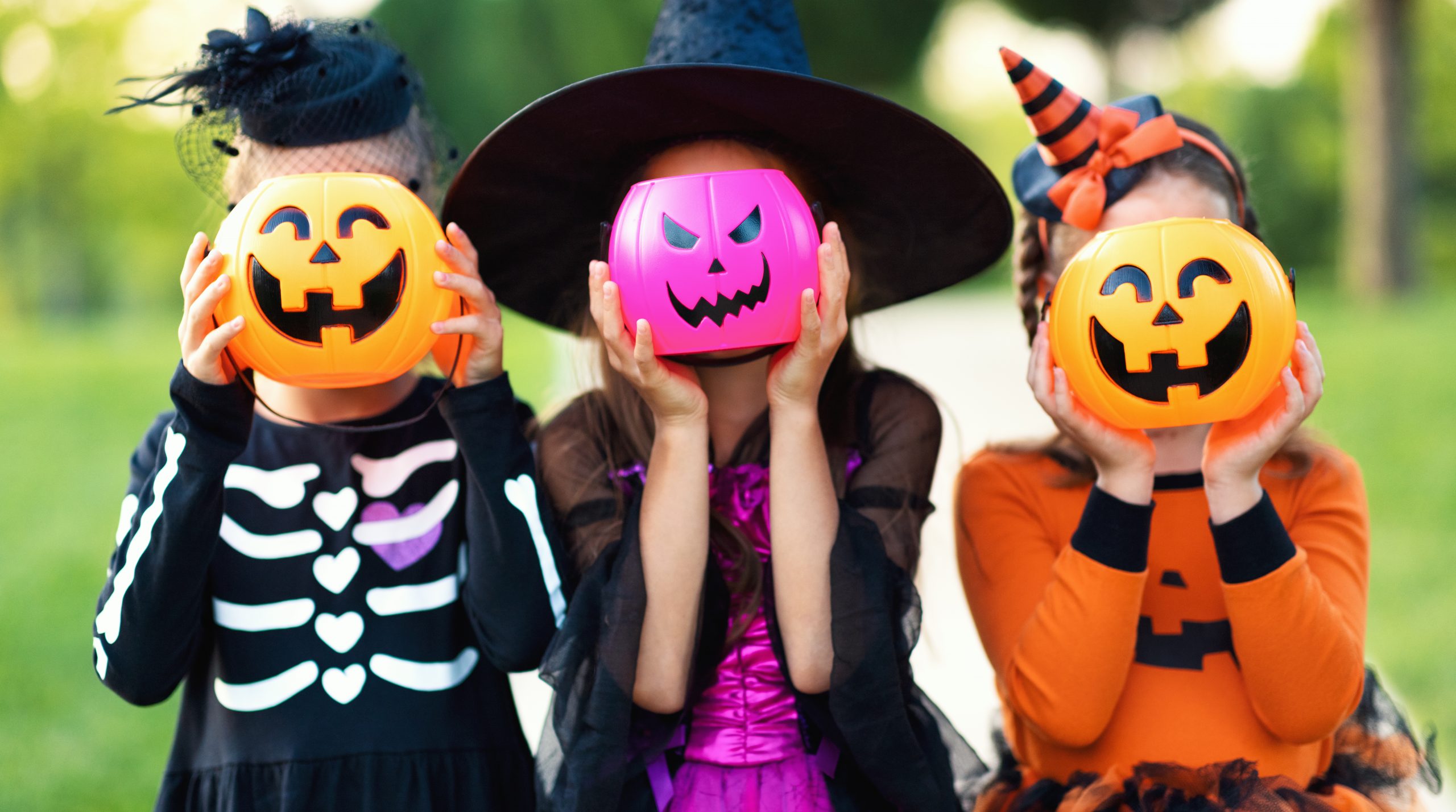 Happy Halloween! funny kids girls   in fancy dress hide their heads behind buckets pumpkins outdoors