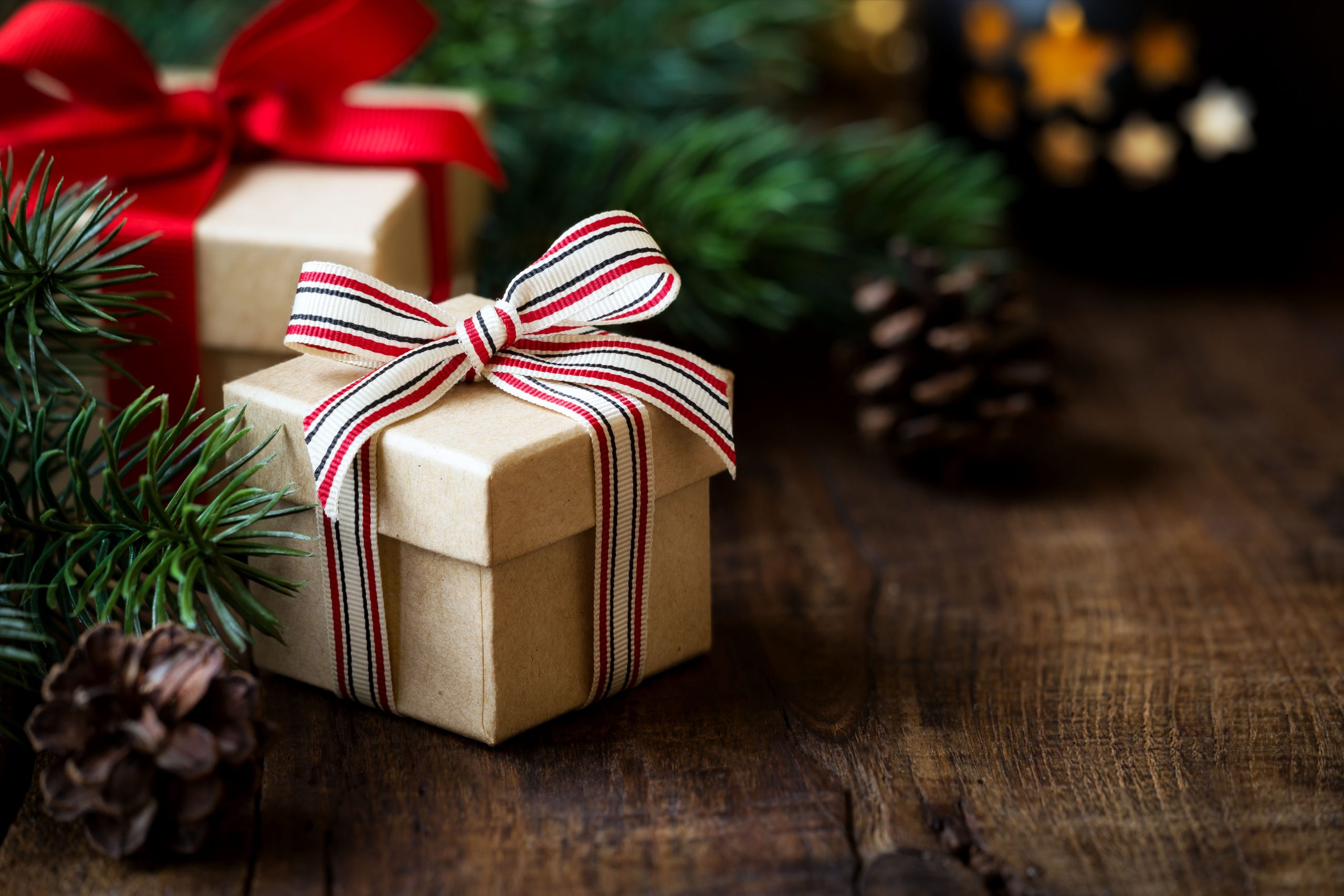 Wrapped Christmas gifts on dark rustic wooden table with pine cones and fir branches. With copy space for your text