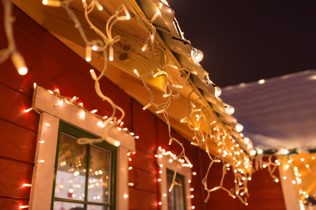 unusual christmas wreath on window. luxury decorated store front with garland lights in european city street at winter seasonal holidays