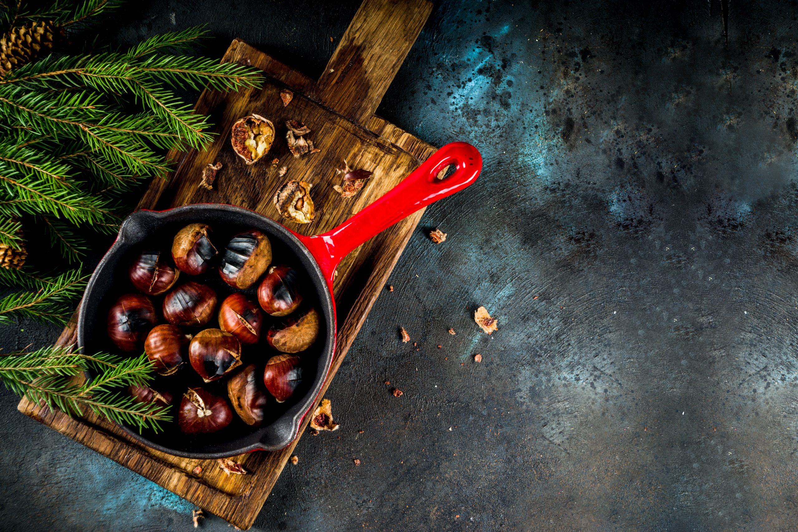 Cracked roasted chestnuts, traditional autumn winter homemade snack, on small chestnut's frying pan, copy space