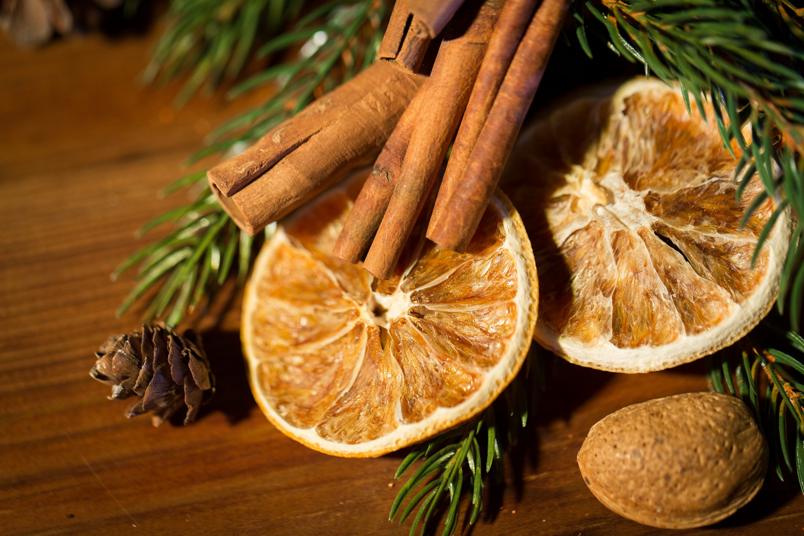 decoration, winter, holidays and new year concept - close up of christmas fir branch with cinnamon and dried orange on wooden table